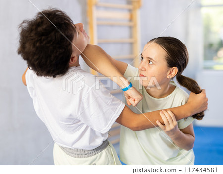 Boy and girl train to perform works out blow to jaw at opponent, while learning self-defense 117434581
