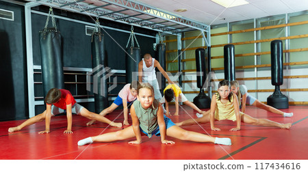 Boys and girls with trainer doing stretching Boys and girls with trainer doing stretching 117434616