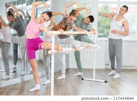 Teenage boys and girls practicing leg stretching exercise during ballet classes Teenage boys and girls practicing leg stretching exercise during ballet classes 117434694