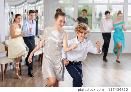 Enthusiastic adolescent girl and boy dancing in pair in dance studio 117434810
