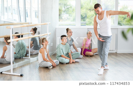 Sportive young male trainer demonstrating professional poses to teenage boys and girls Sportive young male trainer demonstrating professional poses to teenage boys and girls 117434853
