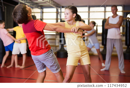 Boy and girl in pair exercising self-defense movements Boy and girl in pair exercising self-defense movements 117434952