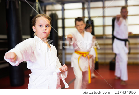 Karate kids in kimono performing kata moves 117434990