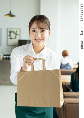 A young female sales clerk handing over a product A young female sales clerk handing over a product 117435141