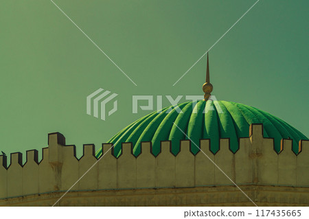 The upper part of building has a large green dome and the tops of the stone wall with observation windows against the yellow blue sky. Exterior of architectural buildings representing cultural values 117435665