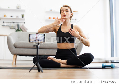 Woman practicing yoga and filming vlog at home 117437009