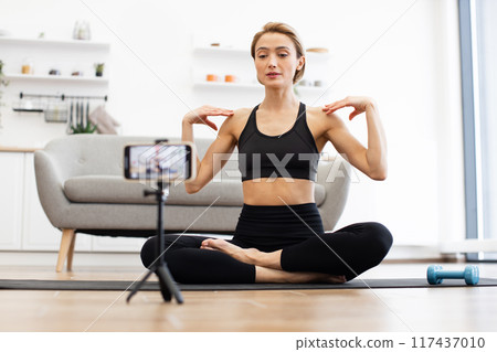Woman practicing yoga at home recording fitness video 117437010