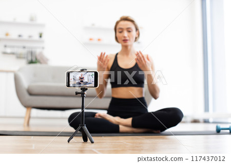 Woman recording online yoga class from home 117437012