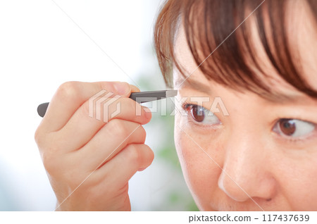 Middle-aged woman taking care of her eyebrows 117437639