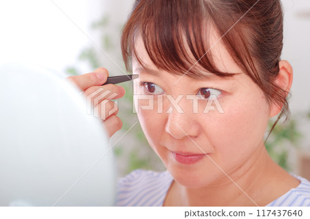 Middle-aged woman taking care of her eyebrows 117437640