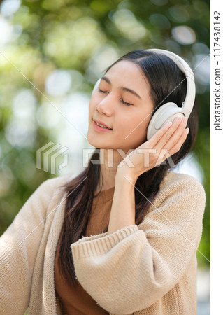 A woman wearing headphones and smiling A woman wearing headphones and smiling 117438142