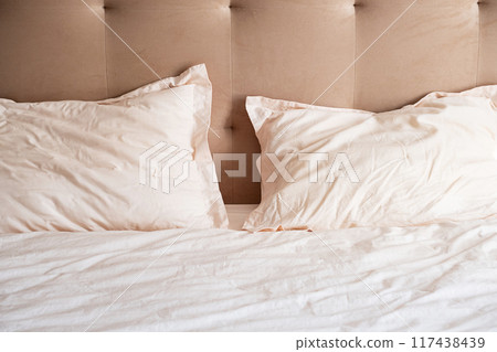 Messy bed with crumpled pillows and sheets on beige headboard. Messy bed with crumpled pillows and sheets on beige headboard. 117438439