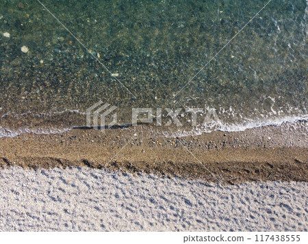 Aerial view from above on calm azure sea and pebbles beach. Small waves on cristal clear water surface in motion blur. Summer ocean sea beach background. Nobody. Holiday, vacation and travel concept 117438555