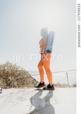 Woman in Orange Sportswear with Yoga Mat Ready for Workout 117438818