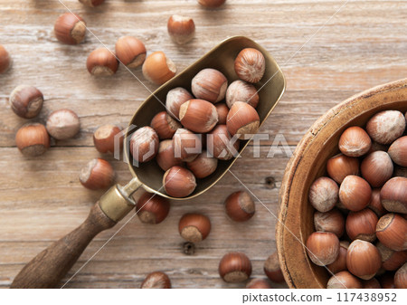 Raw healthy hazelnut nuts in wooden bowl plate with scoop on light background. Raw healthy hazelnut nuts in wooden bowl plate with scoop on light background. 117438952