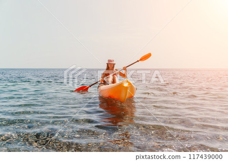 Woman sea kayak. Happy smiling woman paddling in kayak on ocean. Calm sea water and horizon in background. Active lifestyle at sea. Summer vacation. Woman sea kayak. Happy smiling woman paddling in kayak on ocean. Calm sea water and horizon in background. Active lifestyle at sea. Summer vacation. 117439000