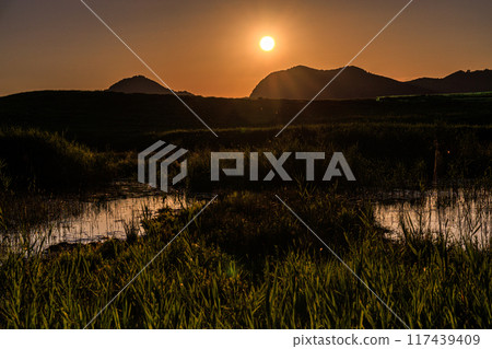 Evening scenery around Okameike Pond in the Soni Plateau in the summer of 2024. The sun sets over the mountains, painting the western sky golden. 117439409