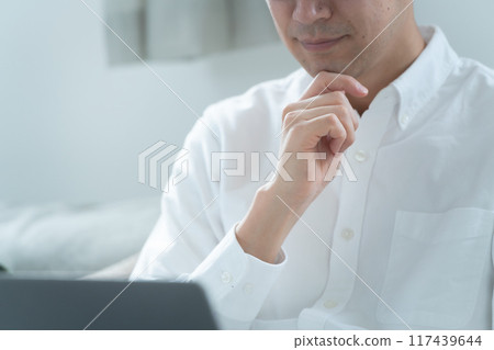 一個男人在客廳工作，手裡拿著電腦 117439644