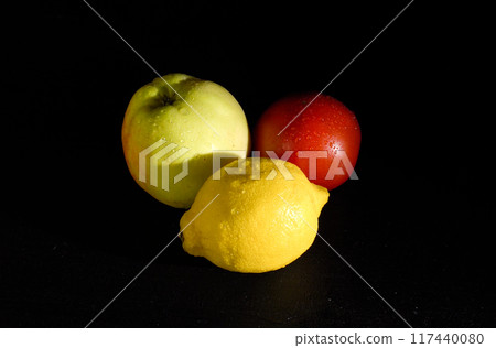 Ripe Yellow Lemon, Apple, and Tomato on a Black Background Ripe Yellow Lemon, Apple, and Tomato on a Black Background 117440080