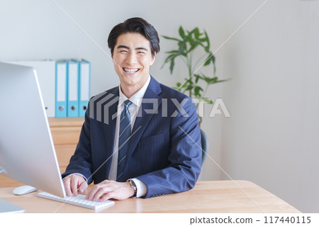 A businessman working on a desktop computer A businessman working on a desktop computer 117440115