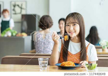 Young woman eating pasta in a cafe Young woman eating pasta in a cafe 117440649