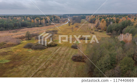 Partly abandoned meadows next to river and autumnal forest  117440669