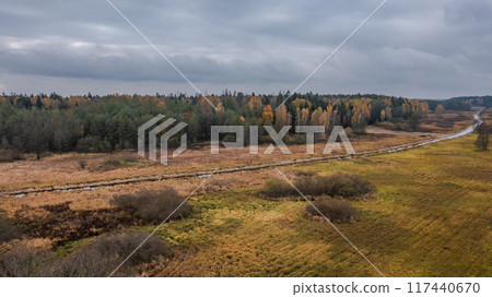 Partly abandoned meadows next to river and autumnal forest  117440670