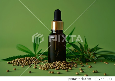 CBD Oil Dropper Bottle with Gold Cap, Surrounded by Hemp Seeds and cannabis Leaves on Green Background CBD Oil Dropper Bottle with Gold Cap, Surrounded by Hemp Seeds and cannabis Leaves on Green Background 117440975