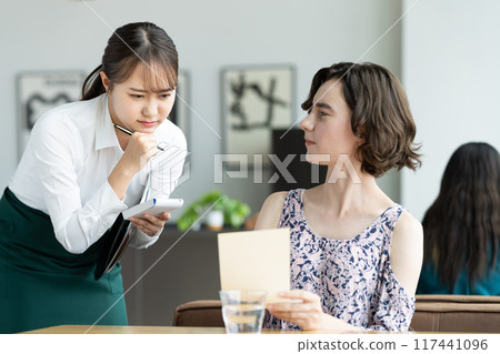 A young store clerk struggling to serve foreign tourists A young store clerk struggling to serve foreign tourists 117441096
