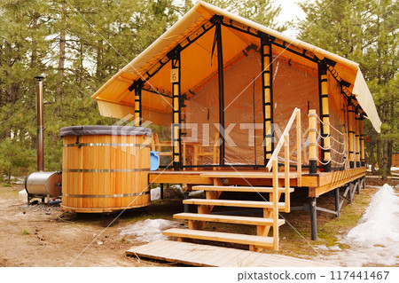 A glamping house with a swimming hot tub in a pine forest.  117441467