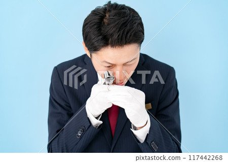 A man examining something with a magnifying glass 117442268