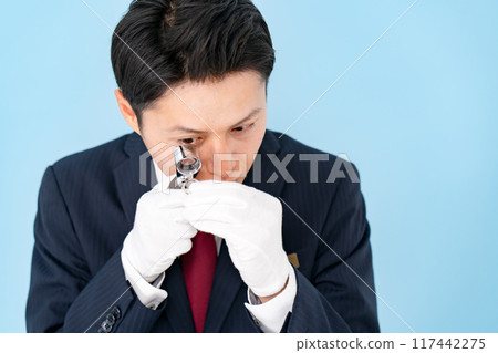 A man examining something with a magnifying glass 117442275