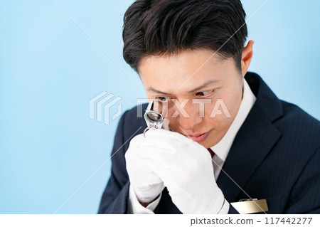 A man examining something with a magnifying glass 117442277