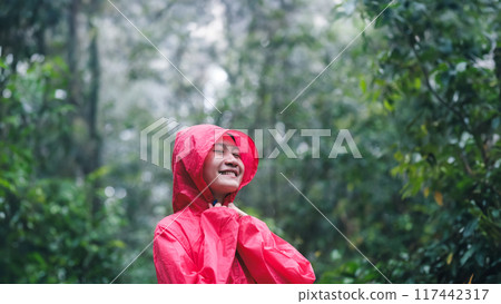 Smiling woman in red raincoat enjoying the forest 117442317