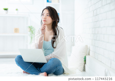 Young woman using a computer in the living room Young woman using a computer in the living room 117443216