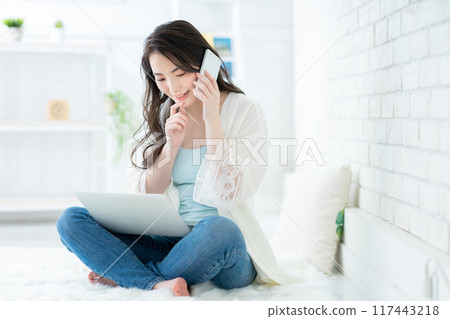 年輕女子在客廳看著電腦打電話 117443218