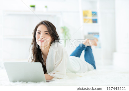 A woman watching a computer in a room A woman watching a computer in a room 117443221
