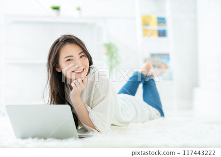 A woman watching a computer in a room A woman watching a computer in a room 117443222