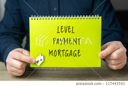 Level payment mortgage concept - loans where the borrower makes equal monthly payments throughout the term of the loan. Real estate and finance. A notepad in male hands and a miniature house 117443541