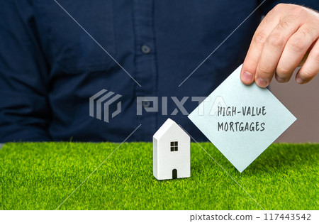 High-value mortgages concept. Loans provided for purchasing luxury or high-cost properties. Real estate and finance. A note in male hands and a miniature house 117443542