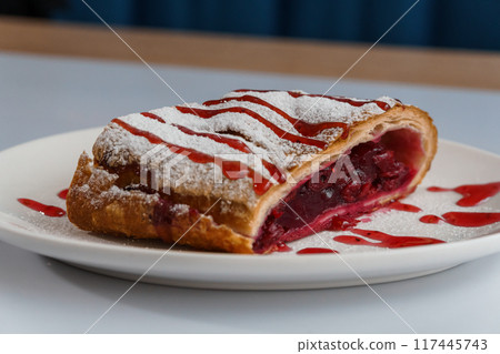 Dessert strudel with cherry and ice cream on a white plate 117445743