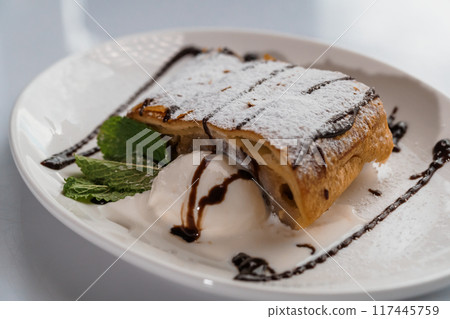 Dessert strudel with chocolate and ice cream on a white plate 117445759