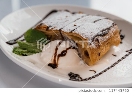 Dessert strudel with chocolate and ice cream on a white plate 117445760