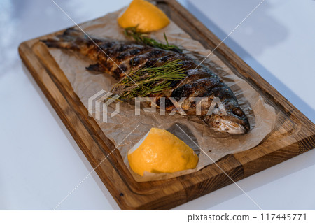 Dorado fish baked with lemon on a barbecue on a wooden board 117445771