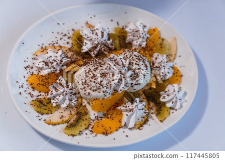 Ice cream with fruits and chocolate on a white plate 117445805