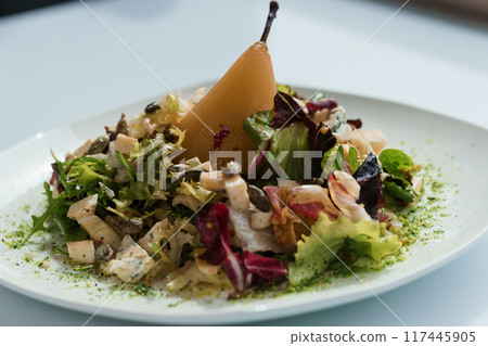 Salad with several types of cheese and baked pear on a white plate Salad with several types of cheese and baked pear on a white plate 117445905