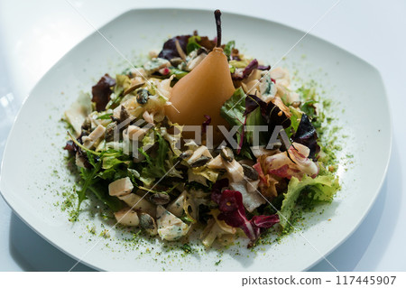 Salad with several types of cheese and baked pear on a white plate Salad with several types of cheese and baked pear on a white plate 117445907
