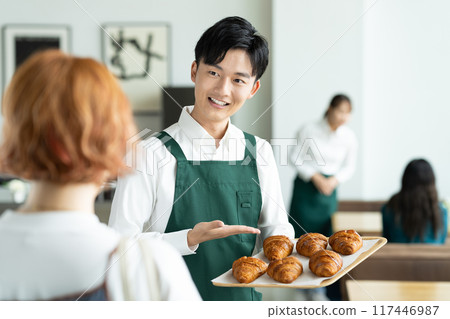 一位年輕的男店員推薦可頌 117446987