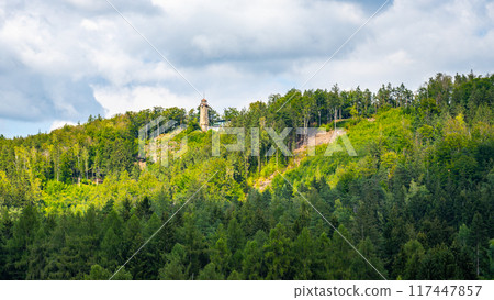 The scenic Prosecsky Hreben lookout tower, standing tall amidst the lush greenery of the Jizera Mountains, is captured under a tranquil sky. 117447857