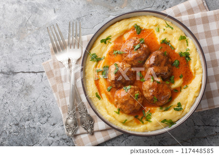 Baked corn porridge with meatballs and spicy gravy close-up in a bowl. Horizontal top view 117448585